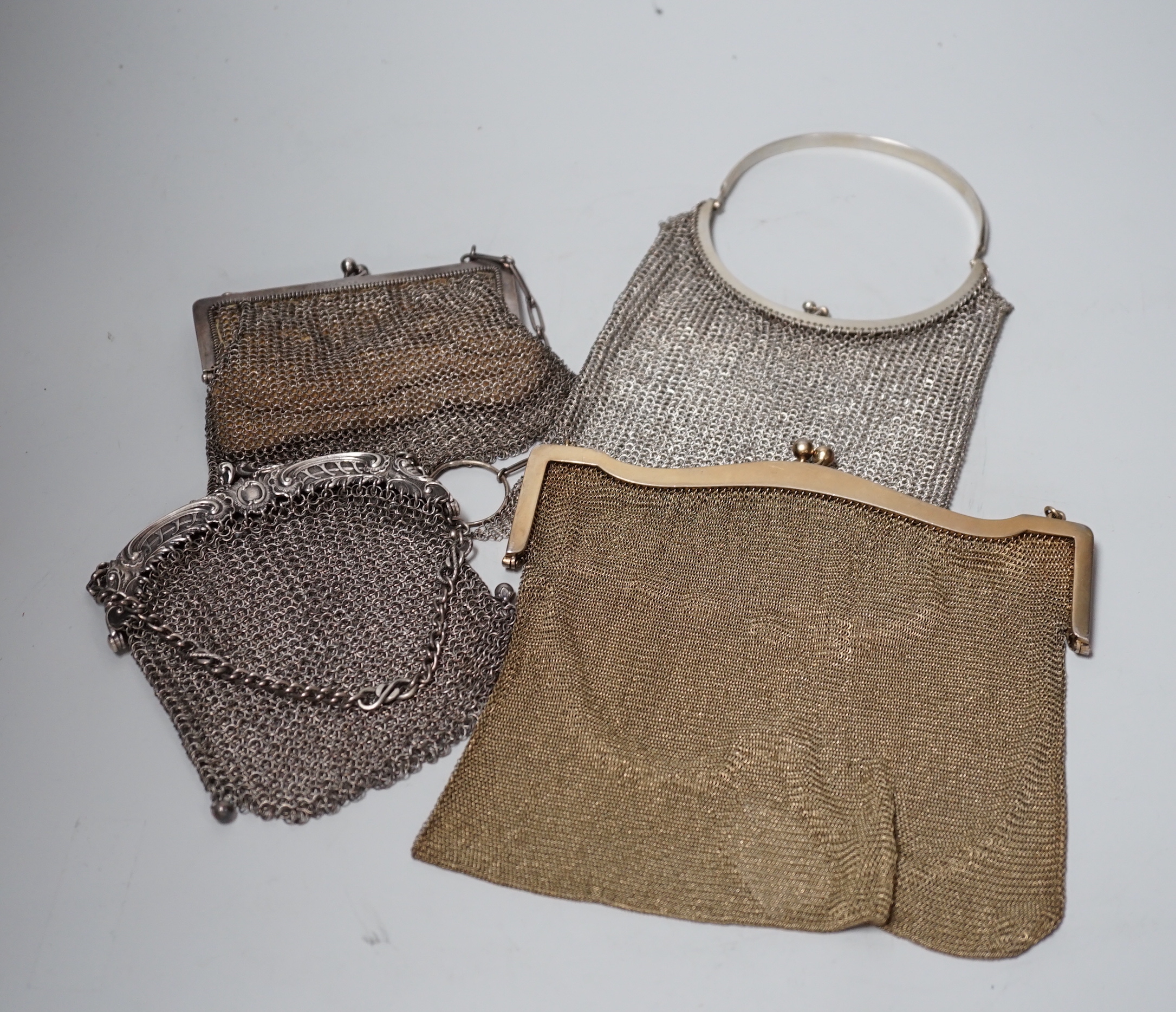 A George V silver gilt mesh evening bag, retailed by Mappin & Webb, Birmingham, 1916 and a smaller silver evening bag, a Chinese white metal mesh evening bag, maker LH and a German 900 standard white metal mesh evening b